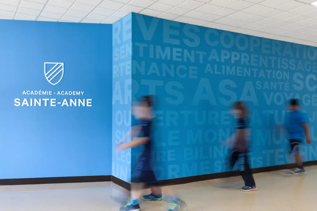 Des étudiants se déplacent devant une murale de l'Académie Sainte-Anne.