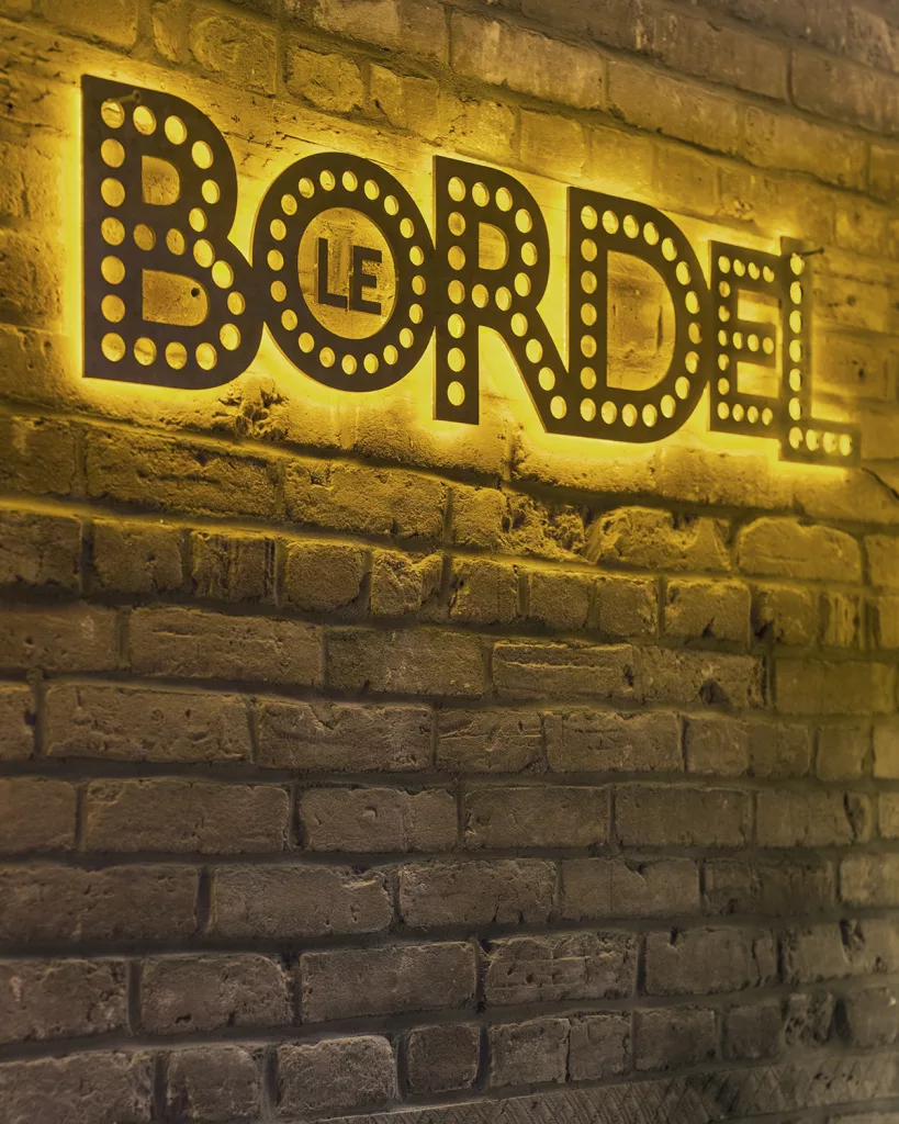 Le logo d'acier rétroéclairé devant le mur de briques du Bordel Comédie Club.