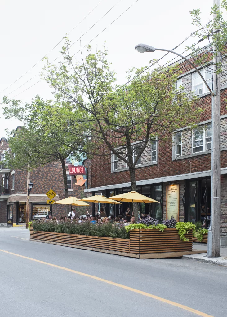La terrasse du Miss Villeray remplie de clients profitant du bon temps sous les parasols jaunes.