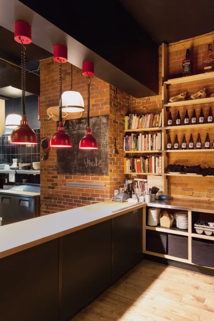 La passe du restaurant O'Chevreuil ou s'alignent trois lampe industrielle d'un rouge vif qui détonne avec les couleurs naturelles du décor.