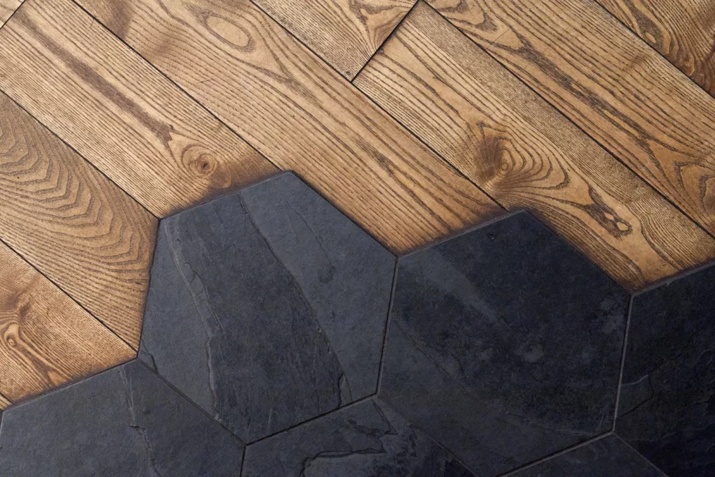 Joinction de tuiles hexagonales d'ardoises et de lattes de bois franc sur le planche du restaurant O'Chevreuil.