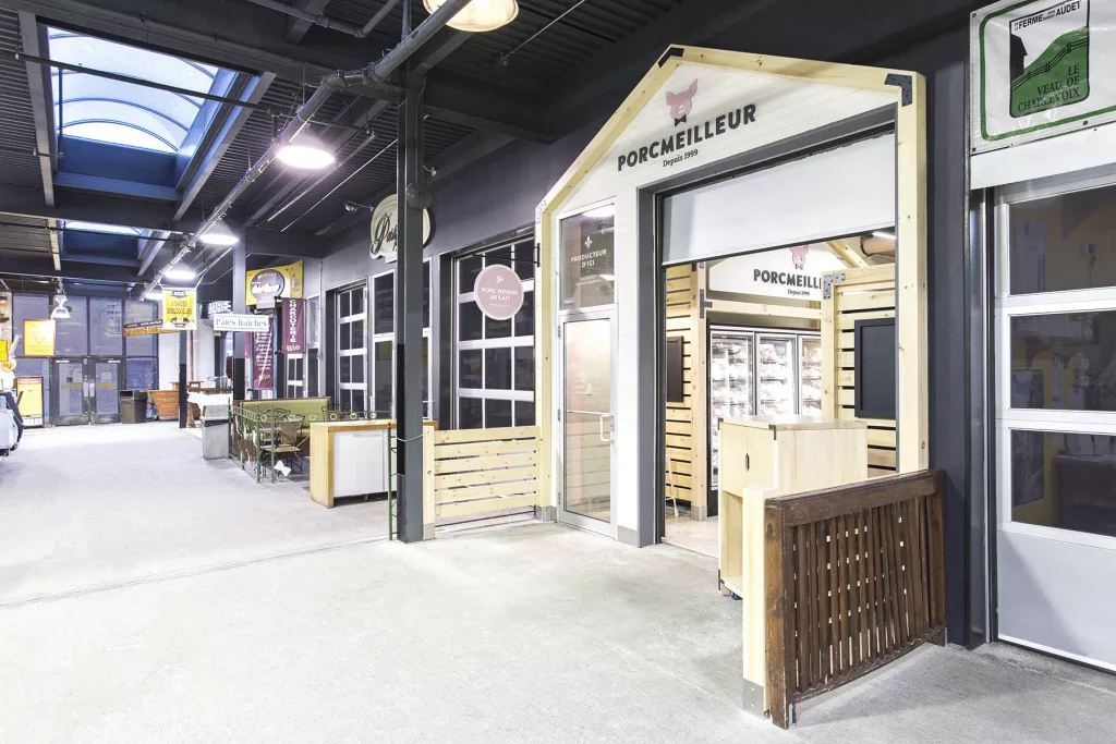 La facade de la boutique Porcmeilleur de démarque de son entourage par sa forme de ferme en bois naturel.