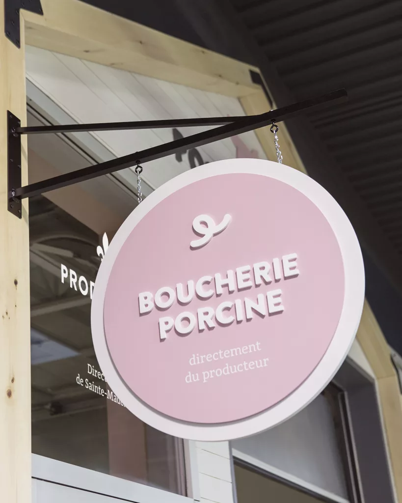Une enseigne suspendue indique clairement aux clients la spécialisation porcine de l'entreprise.