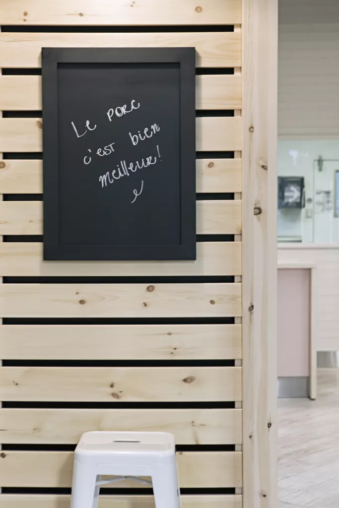 Un tableau noir sur un mur de planche de bois de couleur naturelles de la boutique Porcmeilleur.