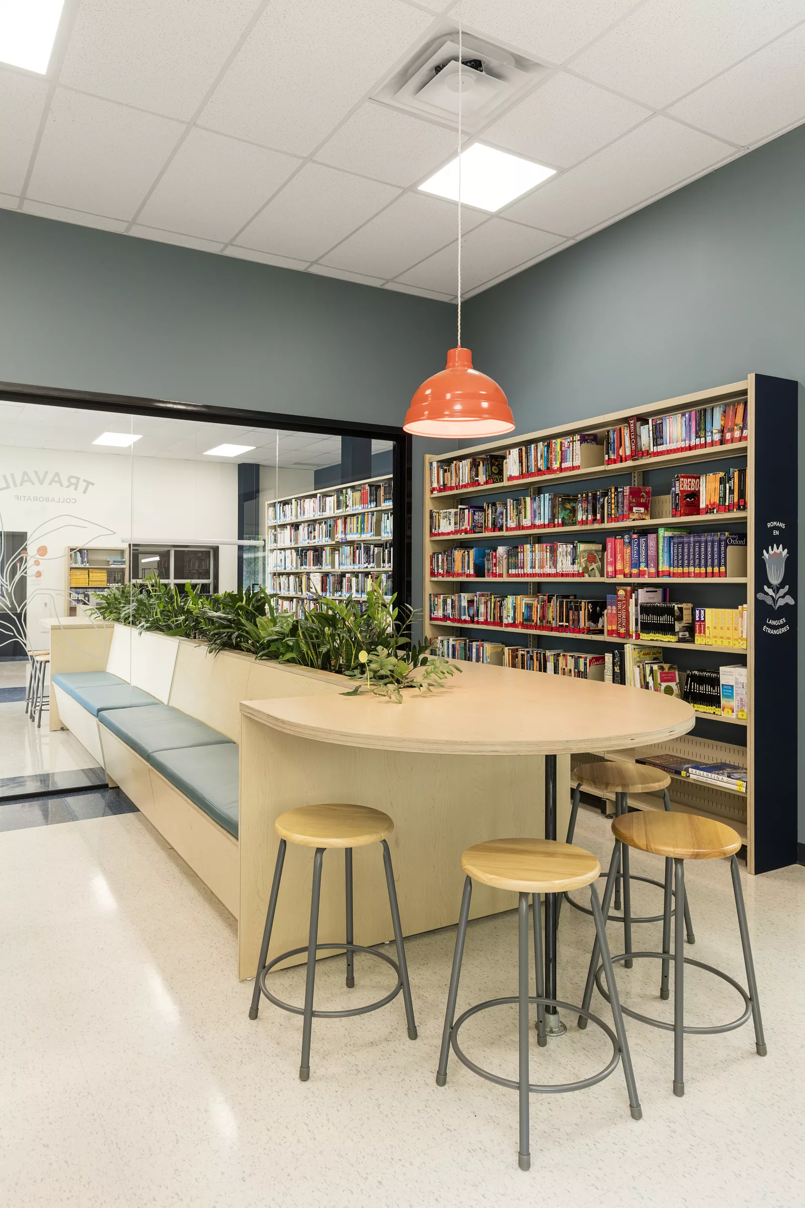 Une vue de la bibliothèque du Collège Saint-Hilaire. On y voit un meuble composé de banquettes et d'un ilôt de travail.