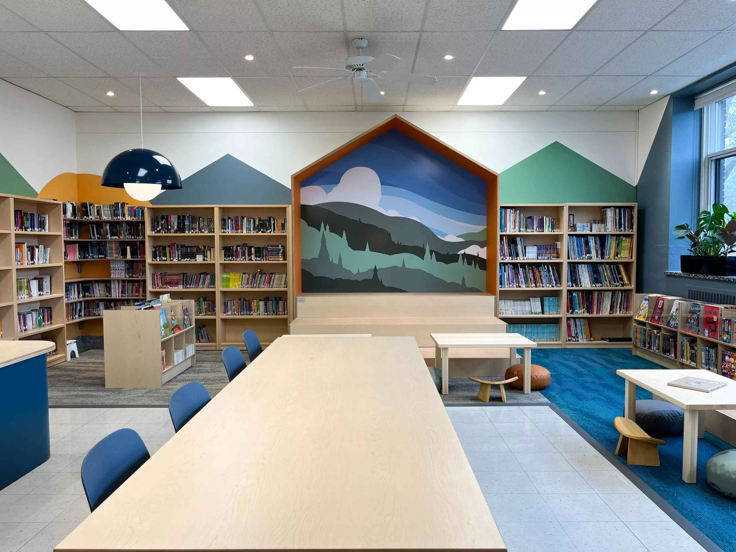 Vue générale de la bibliothèque de l'École Sainte-Anne. On y voit une murale illustrée et du mobilier créé sur mesure par Taktik Design.
