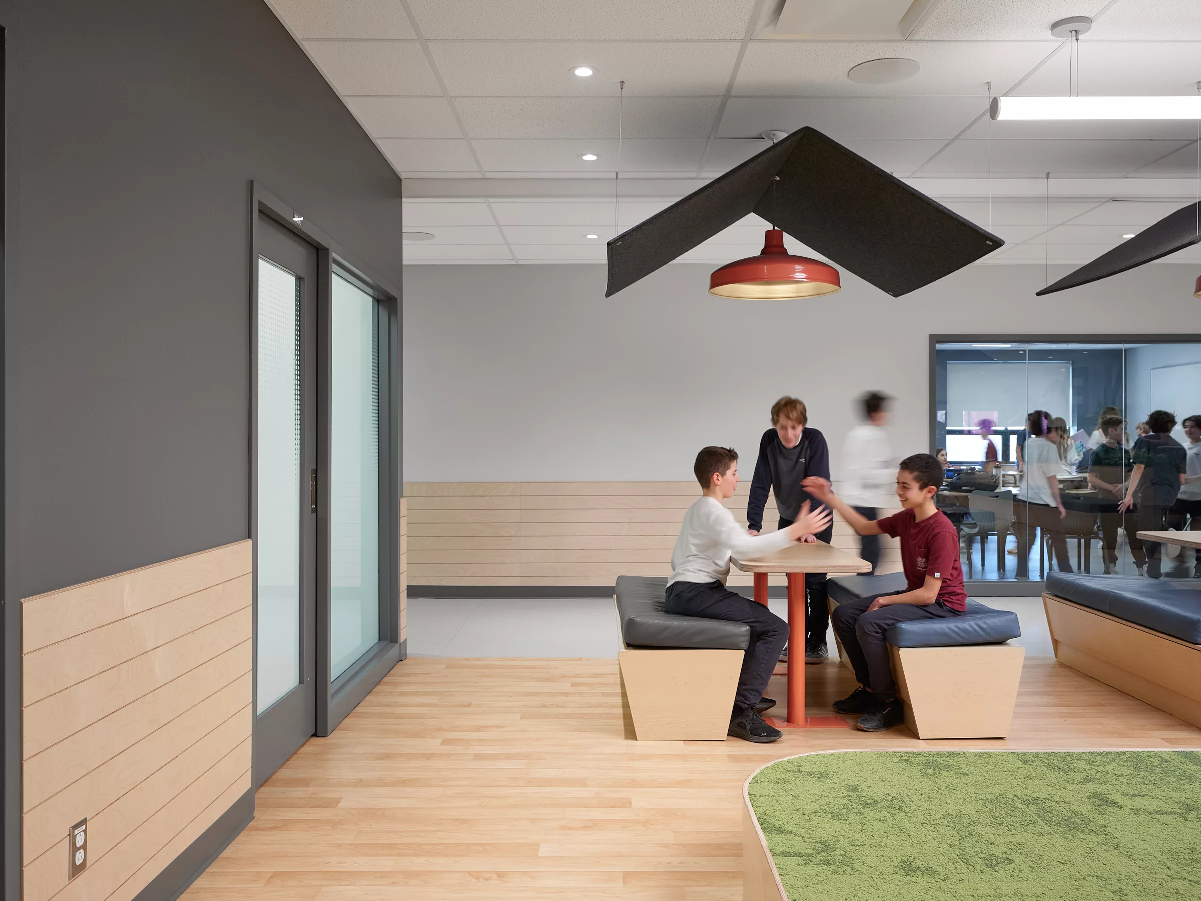 Vue de l'espace estrade et travail du 2e étage au Collège Sainte-Anne, Pavillon Marie Esther. On y voit des élèves utilisant l'espace sur une banquette et table, surplombés d'un toit en feutre suspendu.