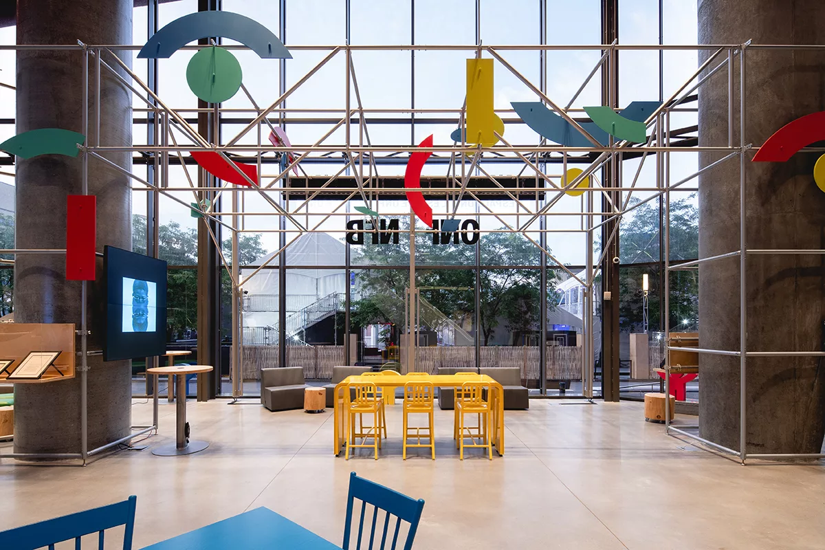 Une vue générale de l'aménagement de l'accueil de l'ONF à l'ilôt Balmoral à Montréal. On y voit une table jaune moderne, centrale dans l'aménagement.