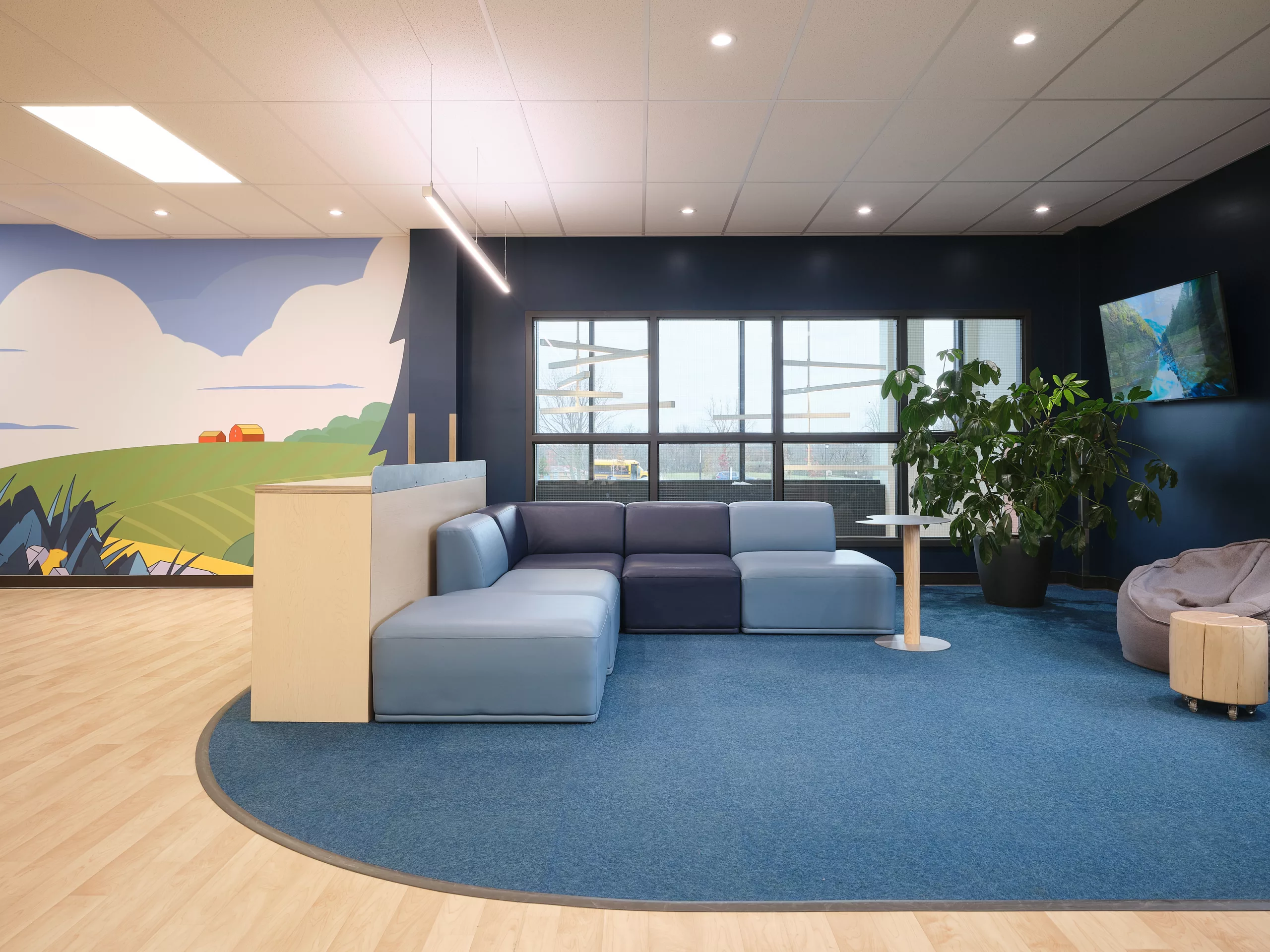 Vue de l'espace détente dans la salle commune du pavillon sportif de l'Externat Sacré-Coeur. On y voit une murale créée par Lucas Saenger en arrière-plan.