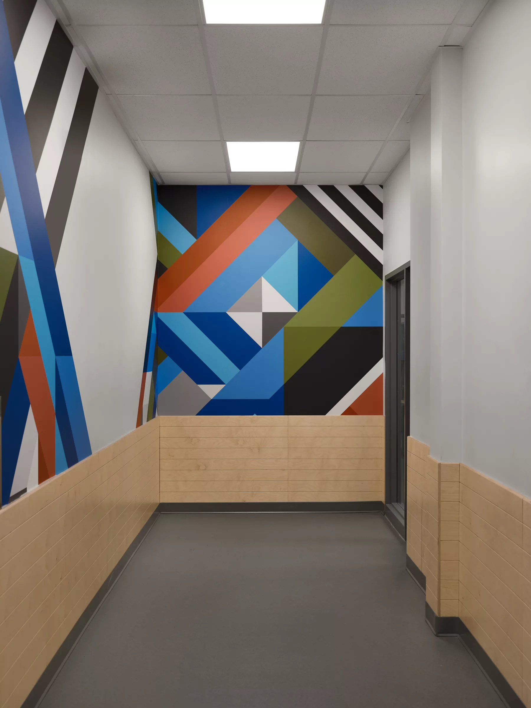 Détail d'une murale créée sur mesure pour l'aménagement. Des formes géométriques aux couleurs du mobilier.