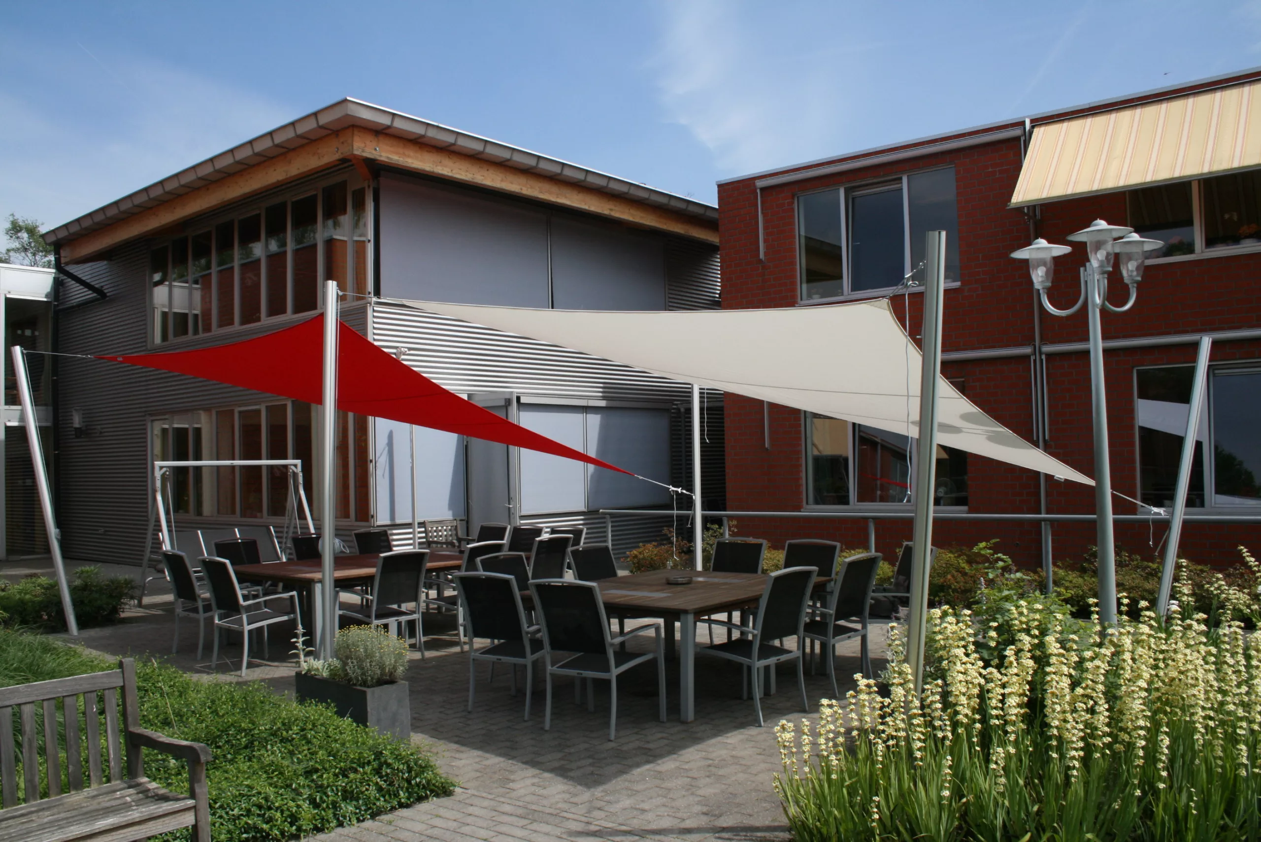 Photographie de parasols de la marque Umbrosa, distribué par Taktik. Des toiles d'ombrages sont placées au-dessus d'une terrasse.