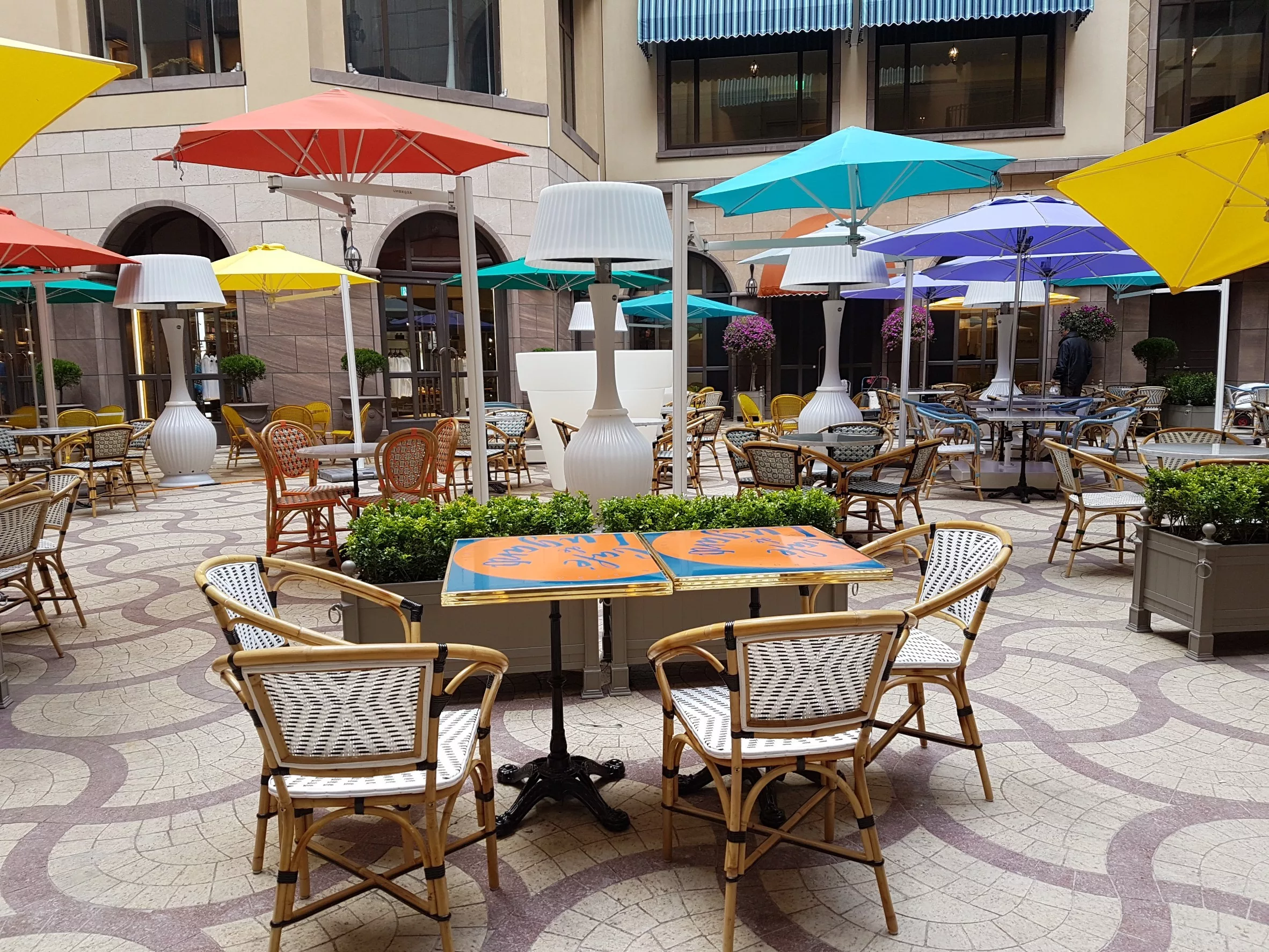 Photographie de parasols de la marque Umbrosa, distribué par Taktik. Des parasols sur pieds colorés décorent une terrasse.